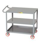 The Little Giant Ergonomic Shelf Truck, with its new handle design, is a gray three-tier utility cart on four red-and-white caster wheels. It stands empty against a plain white background, showcasing its sleek functionality.
