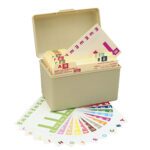 A beige plastic index card box contains Smead AlphaZ NCC Color-Coded Name Labels, A-Z tabs, and various colored lettered cards fanned out on a white surface for easy organization.