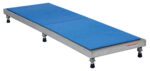The Vestil Adjust Alum Stand 5.75-7.75 H 24X72 is a long rectangular metal platform with adjustable legs, a blue textured surface, measuring 24x72 inches, and can be raised from 5.75 to 7.75 inches in height with a side label.