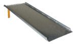 The Vestil Aluminum Hand Truck Dockboard 0.8K 36.25X95.87 ensures secure transitions with a textured surface and raised edges for safety, expertly guiding loads as it slopes from flat ground to an elevated end supported by a yellow beam.