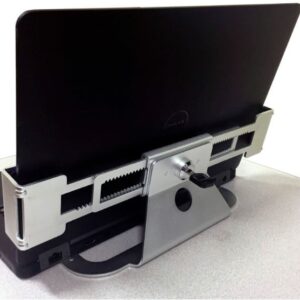 A laptop docked in a metallic horizontal docking station, featuring adjustable sliding grips and a central locking mechanism, placed on a light-colored surface.