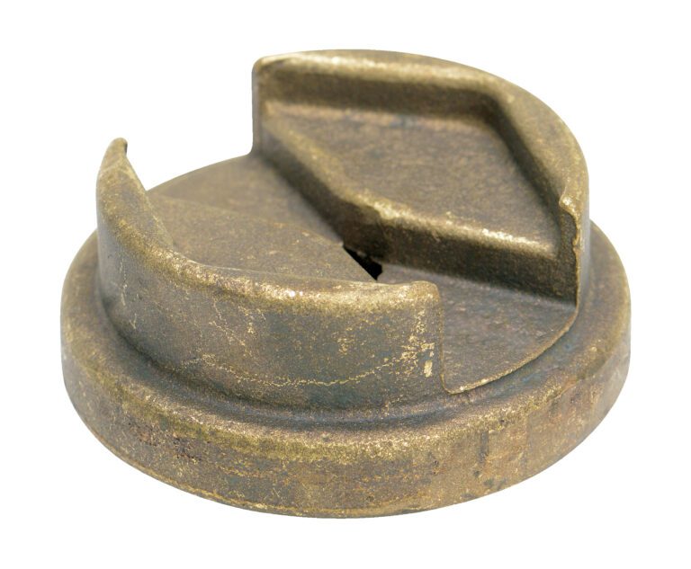 BUNG-S-B1_A.jpg A round, weathered metal object resembling a cap or lid has a wedge-shaped cutout on top, visible scratches, and a dull, brownish patina like an aged Vestil Bronze Drum Bung Socket 3/8 In Drive.
