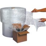 A large MH-USA 1/2 x 12 x 250 perforated air bubble roll is shown with easy hand-tear sheets. An open box filled with bubble wrap and items sits in front, ensuring your valuables are snugly and securely protected.