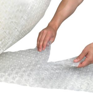 A person carefully handles a sheet of clear, textured MH-USA 1/2 x 48 x 250 Perforated Strong Grade Air Bubble Roll, partially draping it over a surface.