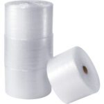 Three MH-USA 5/16 x 12 x 188 Parcel Ready Perforated Air Bubble Rolls are stacked vertically with one roll leaning against them. These semi-transparent rolls, featuring visible bubble texture, are ideal for packaging and cushioning.