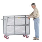A man in safety glasses, a beige shirt, and jeans is pushing a Little Giant Welded Drop-Gate Truck. It has red wheels, a large gray metal mesh design, and a handle. He stands on the right side of the cart.