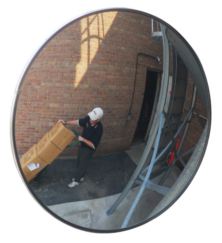 CNVX-30-O_A.jpg A Vestil Convex Mirror Outdoor 30 Ft Distance reflects a person with a cap pushing a hand truck loaded with boxes by a brick wall near an open door, enhancing safety and efficiency in busy outdoor areas.