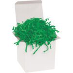 A plain white gift box overflows with vibrant MH-USA 10 lb. Green Crinkle Paper, its cheerful color spilling over the edges and contrasting with the simple box, suggesting its decorative intent.