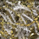 A close-up of MH-USA 10 lb. White and Gold Metallic Blend Crinkle Paper reveals spiral streamers with a shiny, festive texture that reflects light, enhancing the celebratory atmosphere.