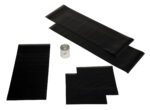 Five black rubber patches of different sizes, included in the Vestil Dock Seal Option Repair Kit, are arranged alongside a small spray can for repairs. The black items stand out against the white background.