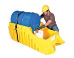 A worker in a hard hat and gloves uses the Vestil Drum Truck Dispensing & Containment Unit to handle a blue drum on a yellow spill containment pallet, pouring liquid into a white bucket while kneeling.