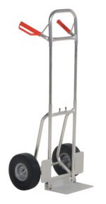 The Vestil Fold-Down Aluminum Hand Truck-Blk Ureth sports a silver frame, two black urethane wheels, and red handles. Its upright design with a flat loading plate ensures rugged traction and efficient transport for various tasks.