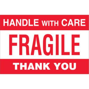 A red and white sign reads HANDLE WITH CARE FRAGILE THANK YOU in bold red letters, similar to MH-USA 4 x 6 - Fragile - Handle With Care Labels (500/Roll).