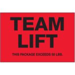 The vibrant MH-USA 2 x 3 - Team Lift fluorescent red labels with bold black text and a warning of THIS PACKAGE EXCEEDS 50 LBS. provide visibility and safety. They come in convenient rolls of 500.