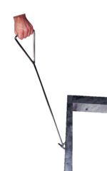 A hand grips a metal hook tool similar to the Vestil Option-Loops/Handles Alum Pallet Dollys sturdy handle, using its triangular grip and long shaft for leverage to lift a manhole lid against a plain white background.