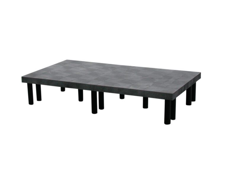 DRP-S-6636_A.jpg This minimalist coffee table, inspired by the Vestil Dunnage Rack Solid Top - 66 X 36, boasts a textured gray-black surface and multiple cylindrical black legs arranged in rows.