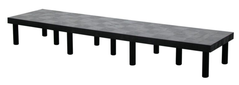 A black, long rectangular bench with a patterned surface and twelve cylindrical legs resembles the Vestil Dunnage Rack Solid Top - 96 x 24. The bench is viewed horizontally at an angle against a white background.