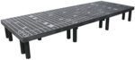 The Vestil Dunnage Rack Vented Top - 96 X 36 is a large industrial metal platform with black cylindrical legs and an evenly spaced grid, designed to elevate the rack for optimal functionality and durability.