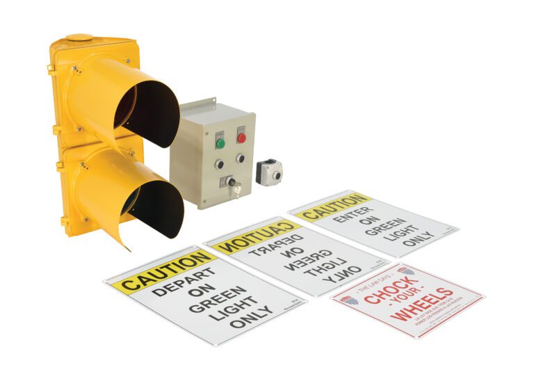 The Vestil Aluminum Housing Dock Traffic System features a yellow light, two empty casings, a control box with buttons and indicators, and four caution signs: DEPART ON GREEN LIGHT ONLY, ENTER ON GREEN LIGHT ONLY, and CHECK YOUR WHEELS.