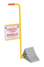 The Vestil Aluminum Wheel Chock has a yellow body, red handle, and a sign stating THE LAW SAYS - CHOCK YOUR WHEELS in English and Spanish, featuring a metal wedge for securely bracing aircraft tires.