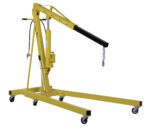 The Vestil Air/Hand Pump Hydraulic Shop Crane 4K is a yellow hydraulic engine hoist with black accents, designed with a lifting arm, chain and hook, and hydraulic cylinder. Its four wheels ensure mobility while the adjustable, extendable arm allows for easy lifting of heavy objects.