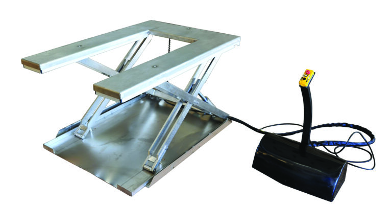 The Vestil Low Profile Stainless Steel Elec U Lift Table has a metallic scissor lift platform with a rectangular surface, powered by a hydraulic mechanism. A cable links it to a black control box featuring yellow and red emergency stop buttons, highlighting its slightly raised position.