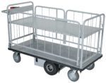 The Vestil Elec Matl Hndl Cart Sides 1-Shelf 28X60 is a large, flat, gray utility cart with railings on all sides and four small wheels. It features a textured platform and a handlebar on one end, making it perfect for transporting heavy or bulky items easily.