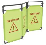 Two bright yellow folding safety signs with black frames resemble the Vestil Folding Fabric Barrier 69 X 1 X 38, each featuring a red triangle with an exclamation mark and SAFETY FIRST text prominently displayed.
