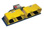 The Vestil Optional Four Pedal Foot Control features two yellow industrial foot pedals on a blue base. The left pedal is labeled TILT, with UP and DOWN options, and the right pedal is marked LIFT, also offering these choices. A gray control box is mounted behind them.