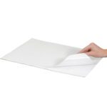 A hand lifts the corner of a stack of MH-USA 12 x 15 Freezer Paper Sheets, showcasing the layers beneath against a white background.