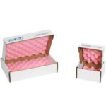 Two white cardboard boxes, open lids exposing pink egg-crate foam inside, are artfully crafted as MH-USA 10 x 6 x 2 Anti-Static Foam Shippers (24/Case). The larger box is on the left, the smaller on the right, offering optimal protective packaging.