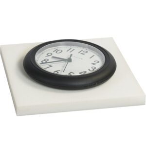 A black-framed wall clock with a white face and black numbers sits on an MH-USA 2 x 24 x 24 White Cloud Foam Sheet from a set of six, displaying the time as around 10:10.