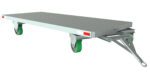 A flat, rectangular metal dolly with a tow bar handle and four green swivel wheels features red and white reflective side strips. This metallic gray surface is ideal for heavy items and resembles the versatile Vestil Fifth Wheel Towable Trailer 10K 60W Poly.