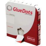 A red and white box of 1/2 Low Tack Glue Dots® - Low Profile (4000/Roll) stands upright with a tear-away section at the bottom exposing the glue dot edge, and the website is visible on the side.