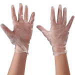 Two hands wearing MH-USA Vinyl Gloves Clear - 5 Mil - Powder Free - Xlarge (100/Case) are raised against a plain background. The transparent gloves fit snugly, highlighting fingers and palm lines.
