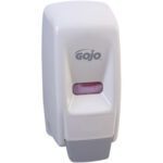 The GOJO® Wall-Mount Dispenser - 800 mL, White, boasts a sleek design featuring the brand name on the front. A rectangular window reveals pink soap inside, all set against a stylish gray base.