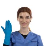 A person with brown hair, wearing blue scrubs and a blue glove on their right hand, is smiling and holding their hand up. The background is plain white.