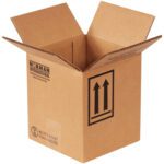 The MH-USA 6 7/8 x 6 7/8 x 7 7/8 cardboard box serves as a 1-gallon hazmat container with flaps upright, featuring Norman International branding, dual arrows for proper orientation, and shipping symbols in black. Sold in bundles of 20.