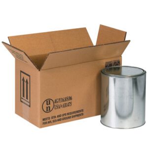 A large metallic paint can sits beside an open MH-USA 14 1/8 x 6 7/8 x 7 7/8 Haz Mat Box, adorned with handling symbols. This versatile box, ideal for air, sea, and ground shipments, is perfect for safely transporting up to two one-gallon containers.