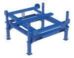 The Vestil Ibc Tilt Stand, featuring a blue metal frame with adjustable legs and a spring mechanism, includes fork pockets for industrial or heavy-duty applications, serving as a robust support structure or essential machine component.
