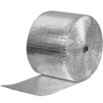 A large roll of MH-USA 12 x 125 Cool Barrier Bubble Rolls is unwinding towards the viewer, displaying its metallic and shiny, quilted silver insulation material. The roll appears thick, with the unwound section lying flat beneath it.