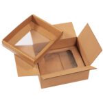 The open 12 x 10 x 5 Korrvu® Suspension Packaging box showcases its interior corrugated texture beside a transparent plastic window on the lid, offering a secure and protective way to display contents.