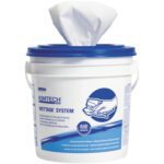 A white bucket featuring the Kimtech® WetTask Prep Wipers (540/Case) label and a blue lid displays user instructions and illustrations, with a cloth protruding from the top opening.