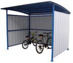 The Vestil Multi-Duty Bicycle Shelter 120 In is a compact blue and white metal structure with a curved roof that accommodates three bicycles. It features corrugated panels that partially enclose the sides and back, while the front remains open.