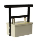 A beige rectangular electric fence tester with a robust black handle offers the efficiency of a Vestil Magnetic Catcher. It features two cylindrical connectors and a yellow label on top, making its simple design ideal for practical outdoor use.