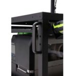 Close-up of a sturdy black metal cart with a handle on the side. On top of the cart is an electronic device with a digital display and multiple buttons. Part of a black and green helmet is also visible beside the device.