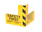 A yellow corner sign with Safety First in English, Spanish, and French and diagonal black stripes complements the durable Vestil Plate Corner Guard Steel 16 X 16 In for improved safety.