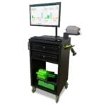 A black mobile workstation with a monitor displaying data charts, a keyboard, and a barcode scanner. The cart has two drawers, storage compartments, and is equipped with wheels for easy mobility.