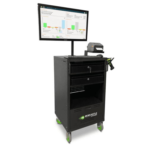 A mobile workstation with a monitor displaying charts and data, a printer, and a handle. It has a black cabinet with drawers and green wheels, labeled Newcastle Systems.