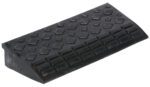 The Vestil Hd Rectangular Rubber Ramp 23.625 Wide includes a black plastic wheel chock with a textured, non-slip surface and angled ramp design. Its diamond-shaped patterns enhance grip to effectively prevent vehicle movement.